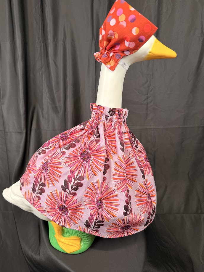 Goose statue wearing pink floral dress and floral hat – side profile view