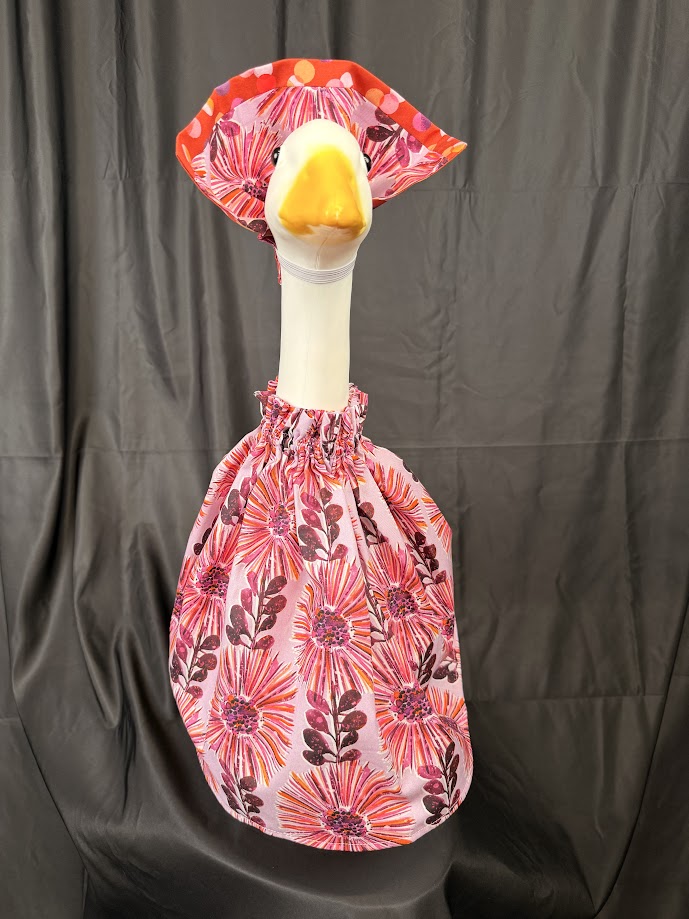 Goose statue wearing pink floral dress and large floral hat – front view