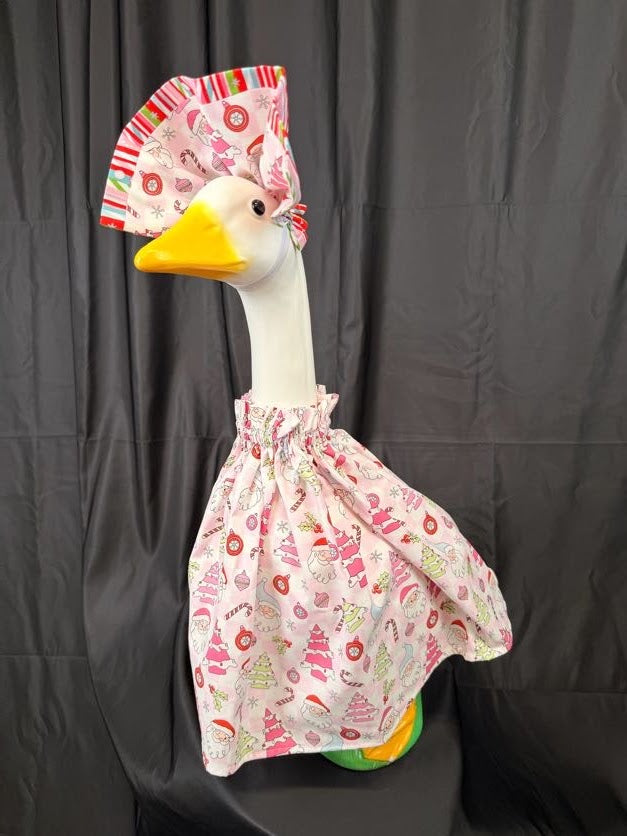 Goose statue wearing pink Christmas print dress and large striped hat – side profile