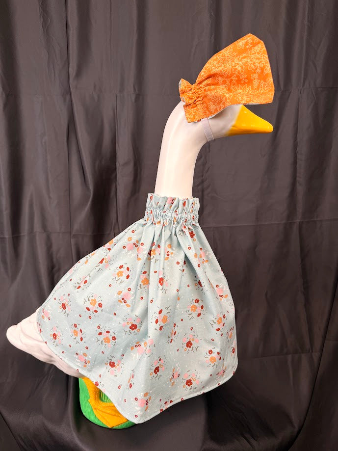 Goose statue wearing blue ditsy floral dress and orange brocade hat – side view