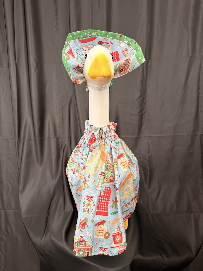 Goose statue wearing light blue Christmas baking dress and large green holiday hat – front view 2