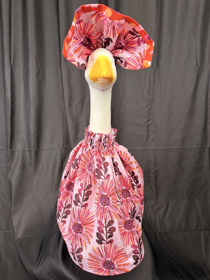 Goose statue wearing pink floral dress and red polka dot hat – side view
