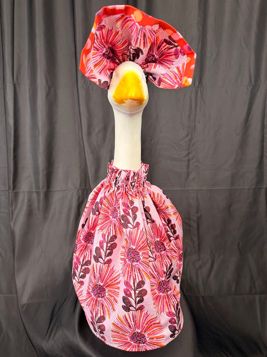 Goose statue wearing pink floral dress and red polka dot hat – side view