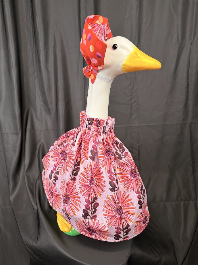 Goose statue wearing pink floral dress and floral hat – front view
