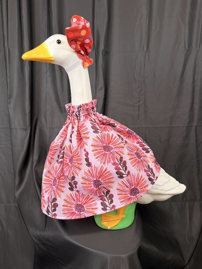 Goose statue wearing pink floral dress and red polka dot hat – back view