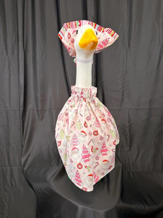 Goose statue wearing pink Christmas print dress and striped holiday hat – front view