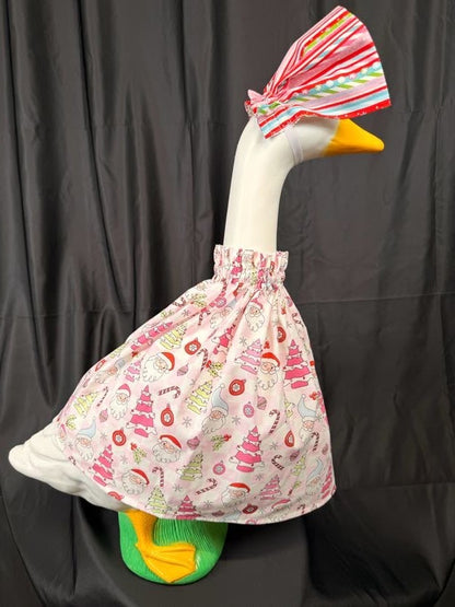 Goose statue wearing pink Christmas print dress and striped hat – side view