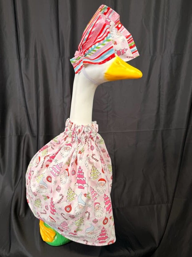 Goose statue wearing pink Christmas print dress and striped hat – three-quarter side view