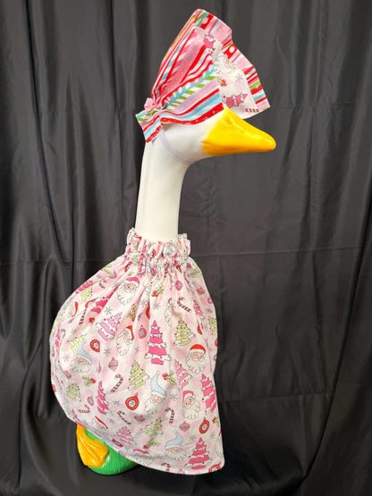 Goose statue wearing pink Christmas print dress and striped hat – three-quarter side view