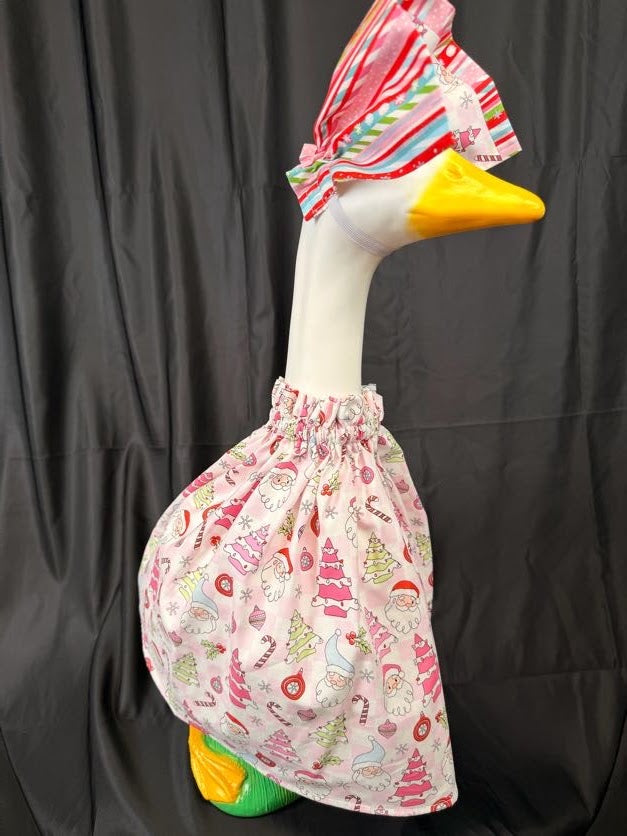 Goose statue wearing pink Christmas print dress and striped hat – angled side view
