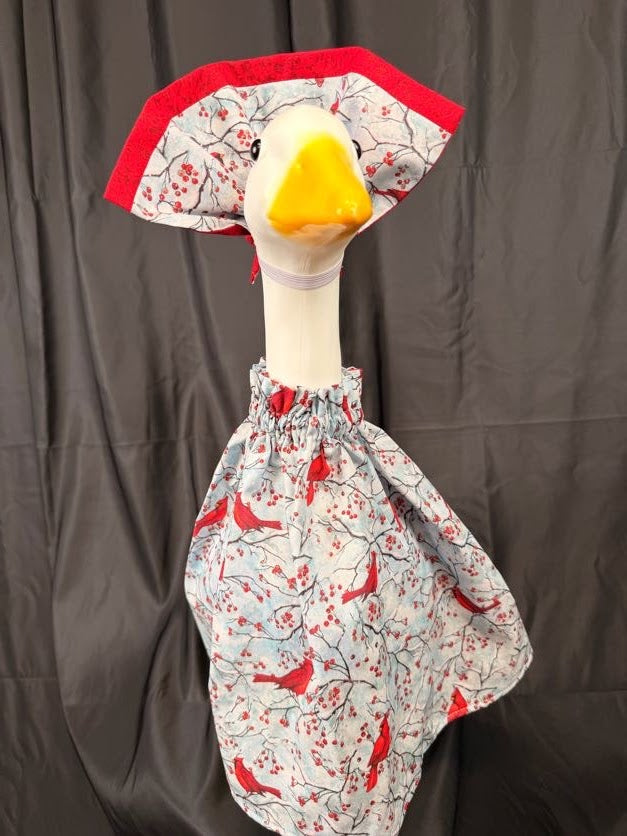 Goose statue wearing cardinal and berry print dress with solid red hat – front side view