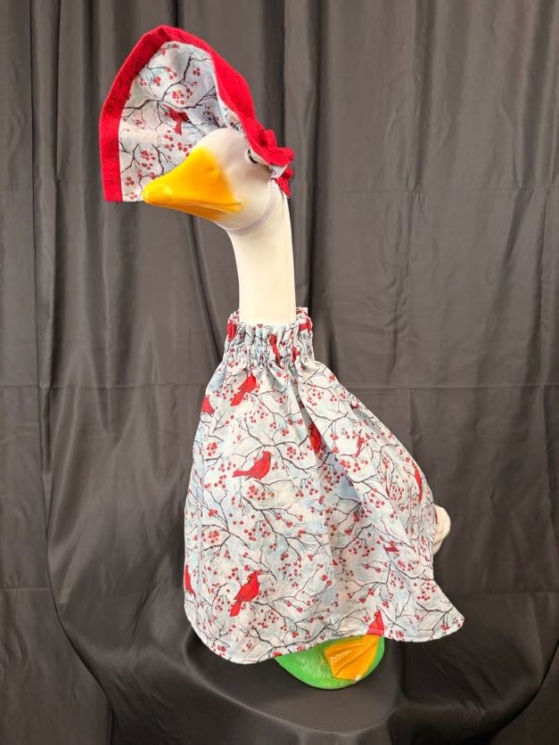 Goose statue wearing cardinal and berry print dress with solid red hat – back side view