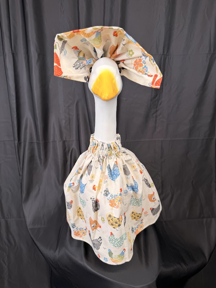 Goose statue wearing cream chicken print dress and floral hat – side view