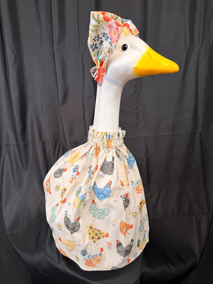 Goose statue wearing cream chicken print dress and floral bonnet – three-quarter view