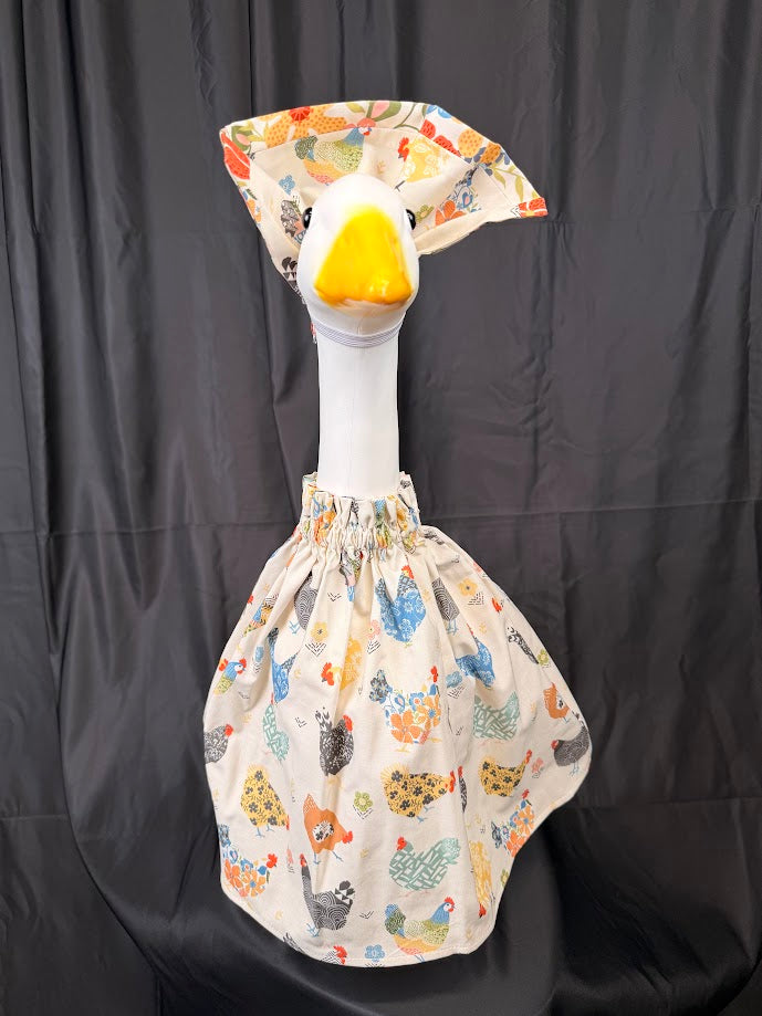 Goose statue wearing cream chicken print dress and small floral hat – angled side view