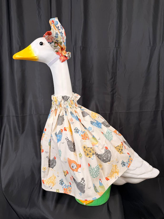 Goose statue wearing cream chicken print dress and floral hat – back side view