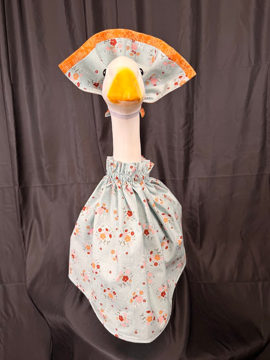 Goose statue wearing blue ditsy floral dress and large orange brocade hat – front view