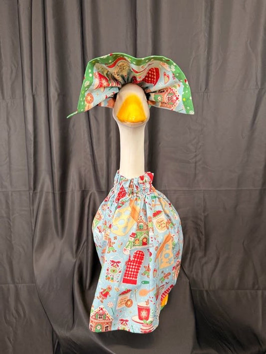 Goose statue wearing light blue Christmas baking print dress and large green holiday hat – front view