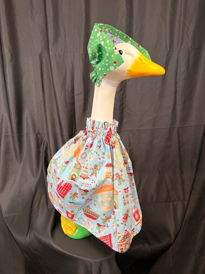 Goose statue wearing light blue Christmas baking dress and green hat – angled side view