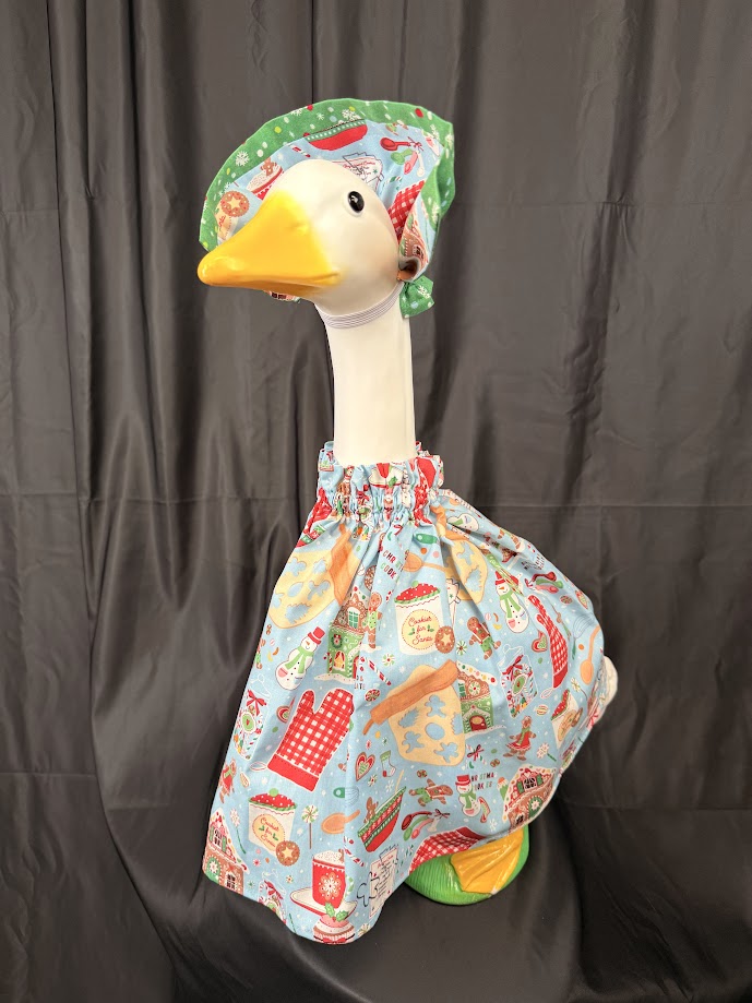 Goose statue wearing light blue Christmas baking dress and green hat – side profile