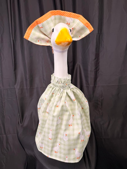Goose statue wearing sage green gingham goose print dress and large orange polka dot hat – front view