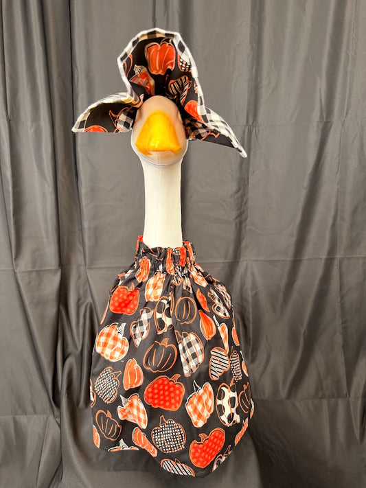 Goose statue wearing black patterned pumpkin dress and large reversible buffalo check hat – front view