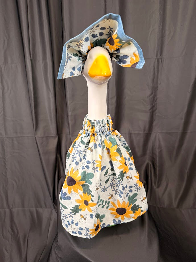 Goose statue wearing white sunflower bee botanical dress and large reversible blue chambray hat – front view