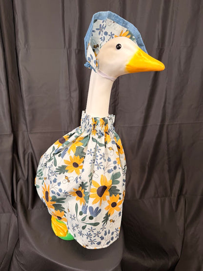 Goose statue wearing white sunflower bee botanical dress and blue chambray/sunflower hat – angled side view