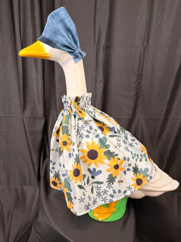 Goose statue wearing white sunflower bee botanical dress and blue hat – side profile