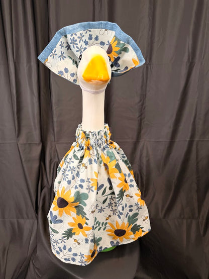 Goose statue wearing white sunflower bee botanical dress and wide reversible blue hat – front view