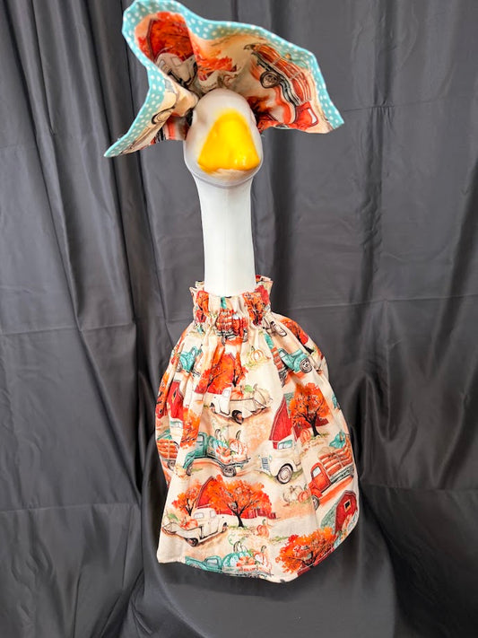 Goose statue wearing cream vintage farm truck dress and large reversible teal polka dot hat – front view